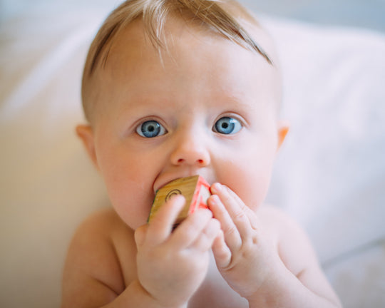 bébé aux yeux bleu qui mange un cube